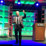 Harley Gordon speaking on stage at an industry conference